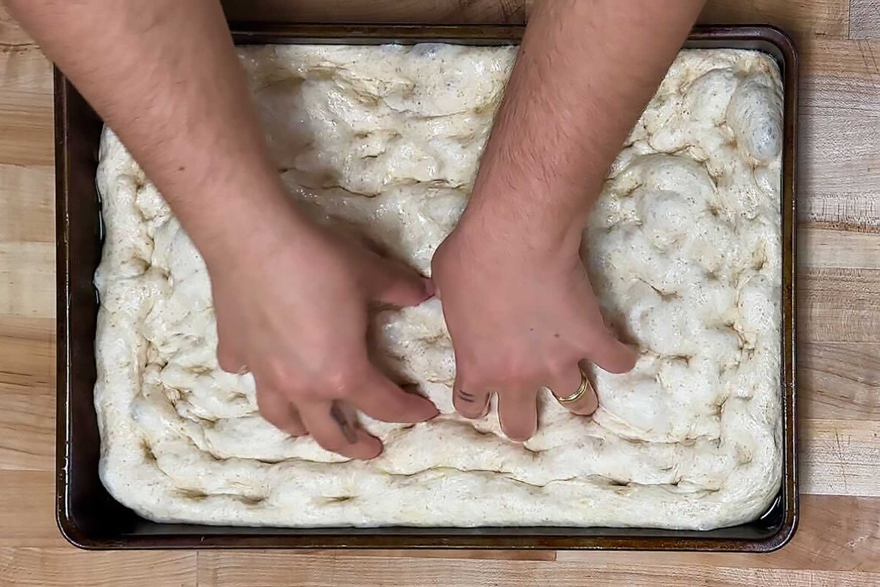 hands dimpling focaccia