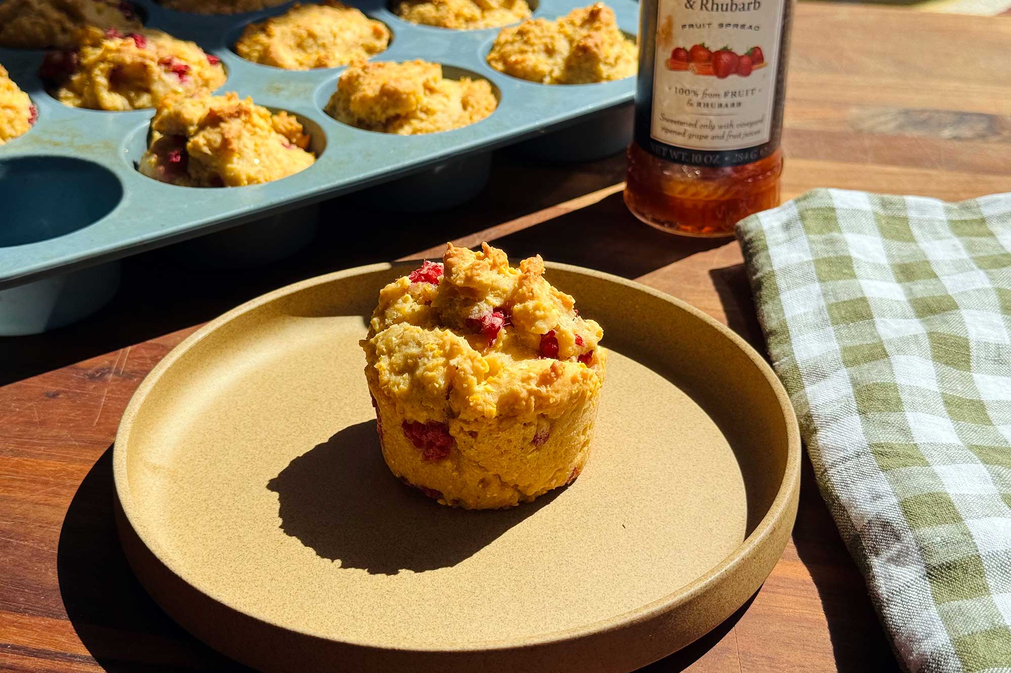 corn muffin with berries on plate in sun