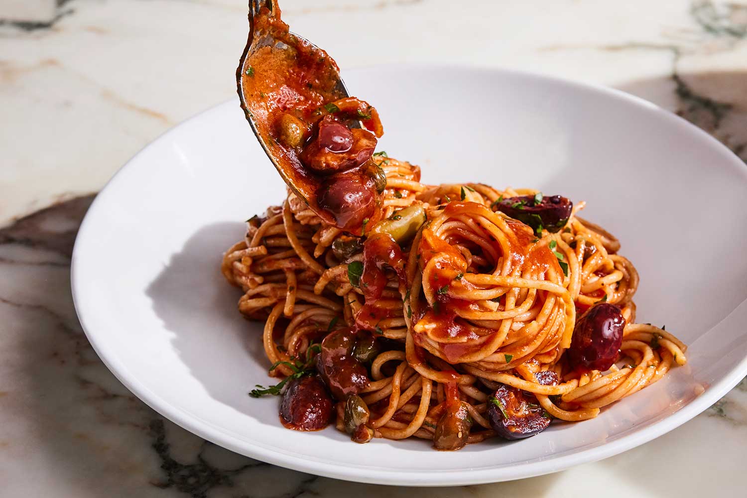 spaghetti puttanesca with spoon