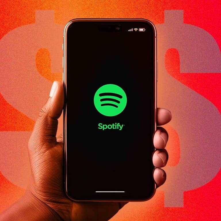 Hand holding phone displaying the Spotify logo. Dollar signs are repeating across the background.