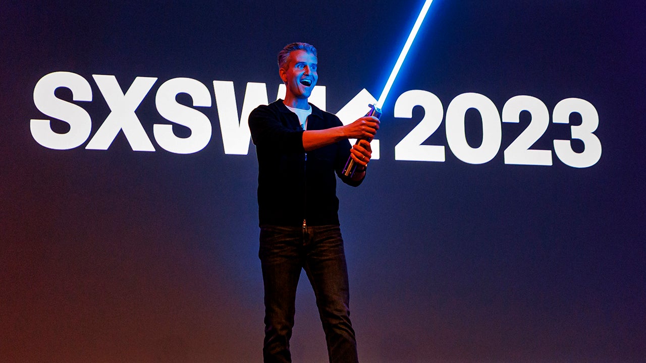 What is SXSW - Andy Wenstrand holding a light saber and speaking at the Creating Happiness The Ar and Science of Disney Parks Storytelling