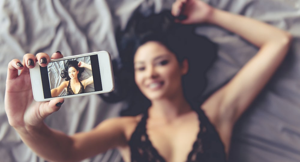 is onlyfans worth it - a woman laying on her back taking a selfie