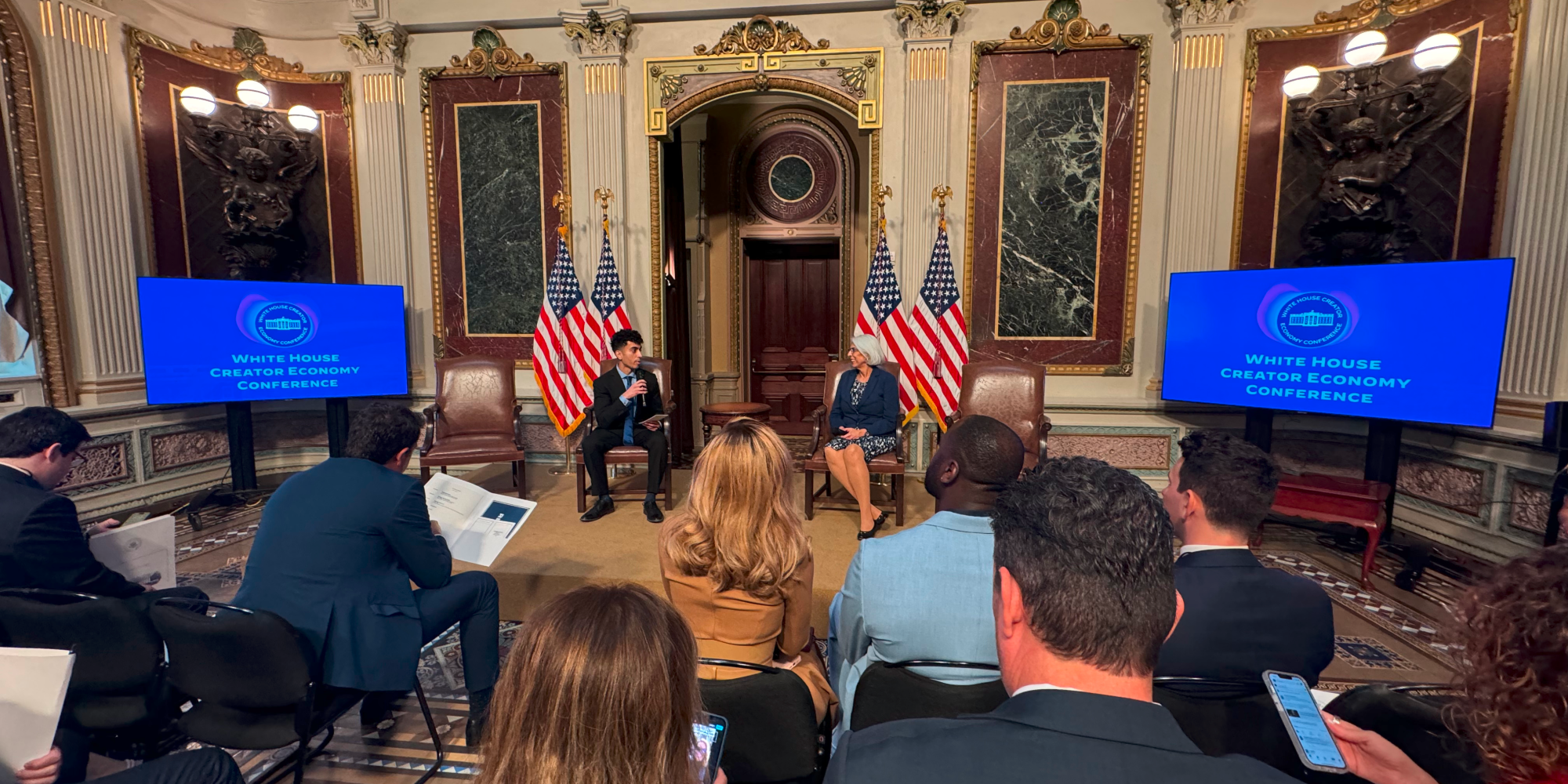 Gohar Khan and Dr. Arati Prabhakar sitting on chairs speaking next to two screens that read White House Creator Economy Conference