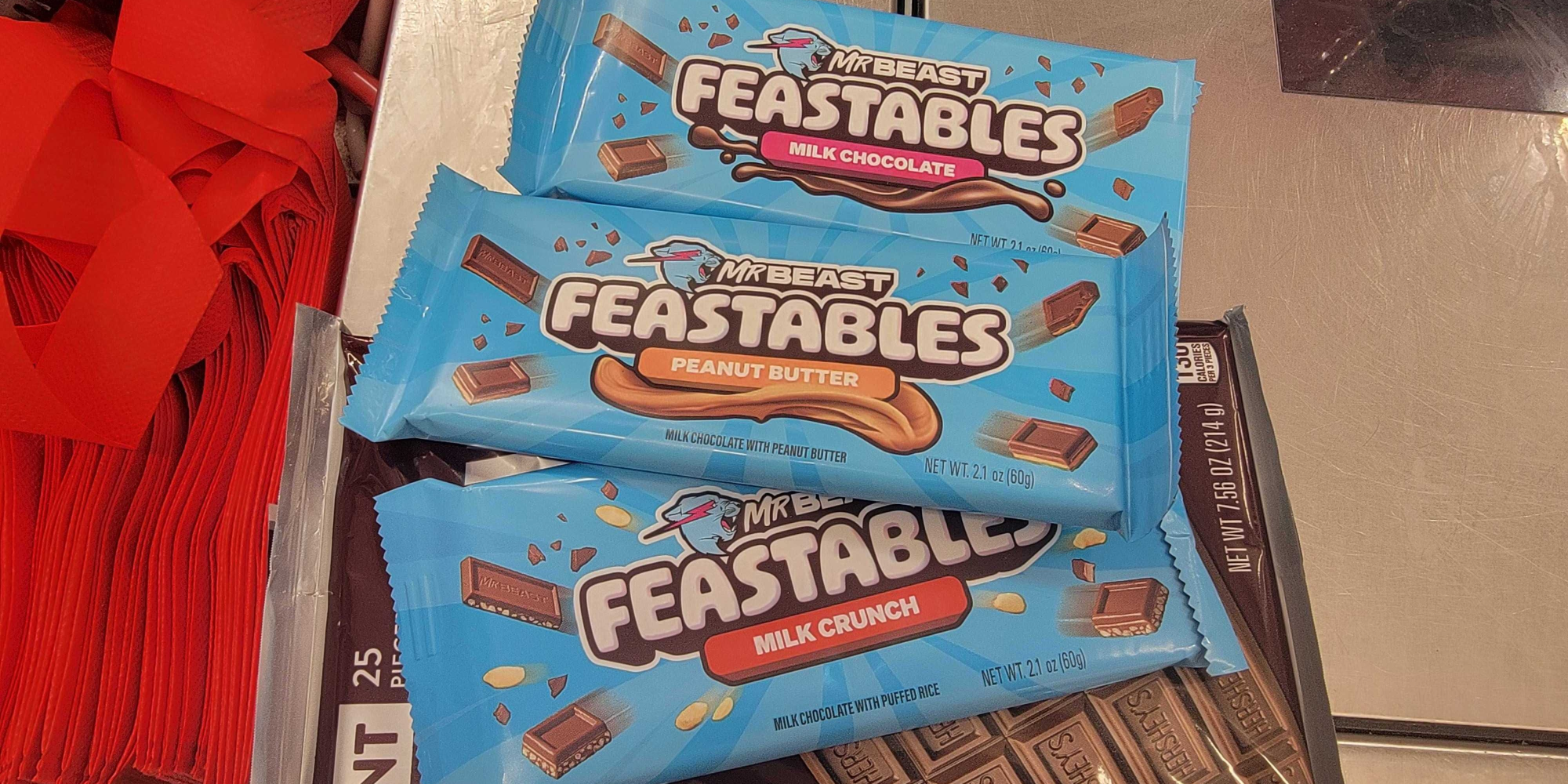feastables milk chocolate, peanut butter, and milk crunch flavors next to a hersheys bar