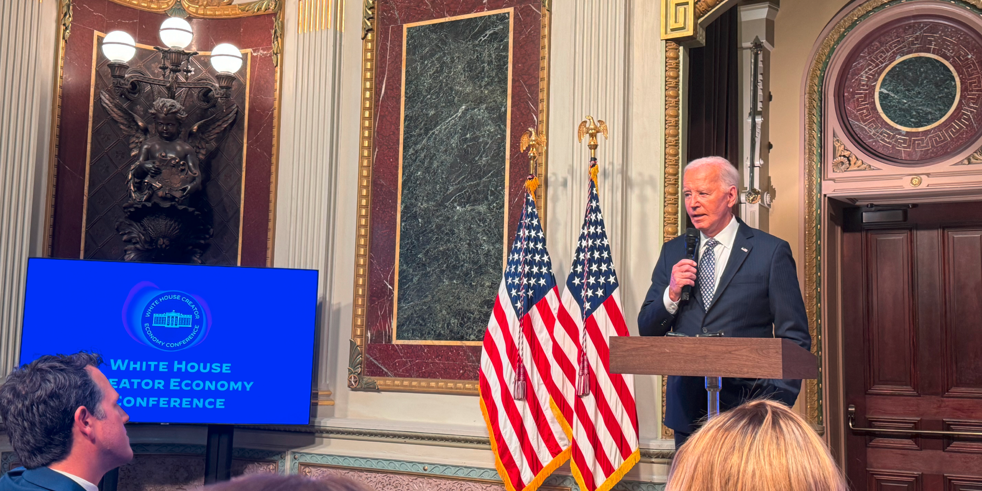joe biden speaking at podium next to a screen that reads white house creator economy conference