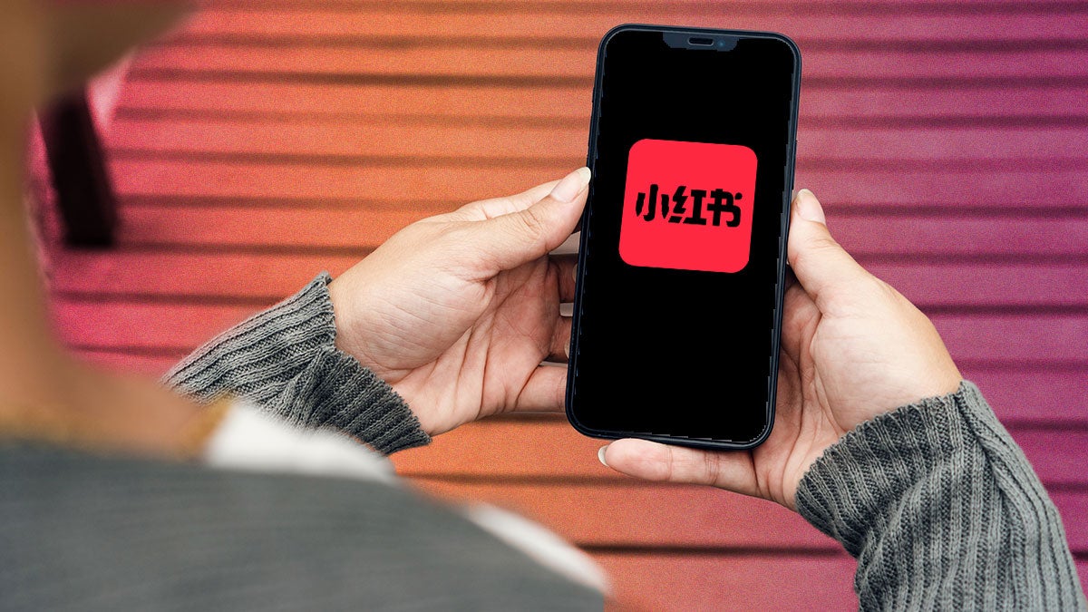 design with a person holding a phone with the App RedNote one it