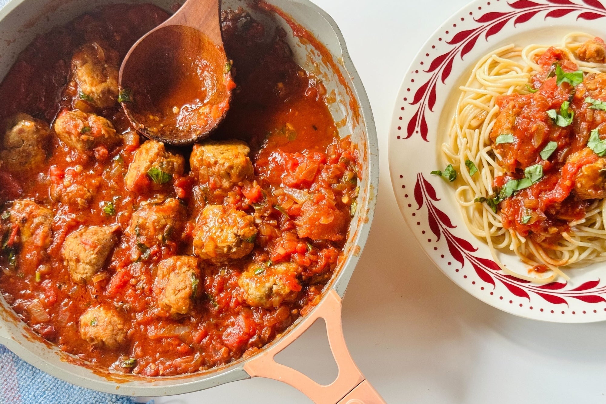 Pork and lentil meatballs in a pot beside a bowl of spagetti